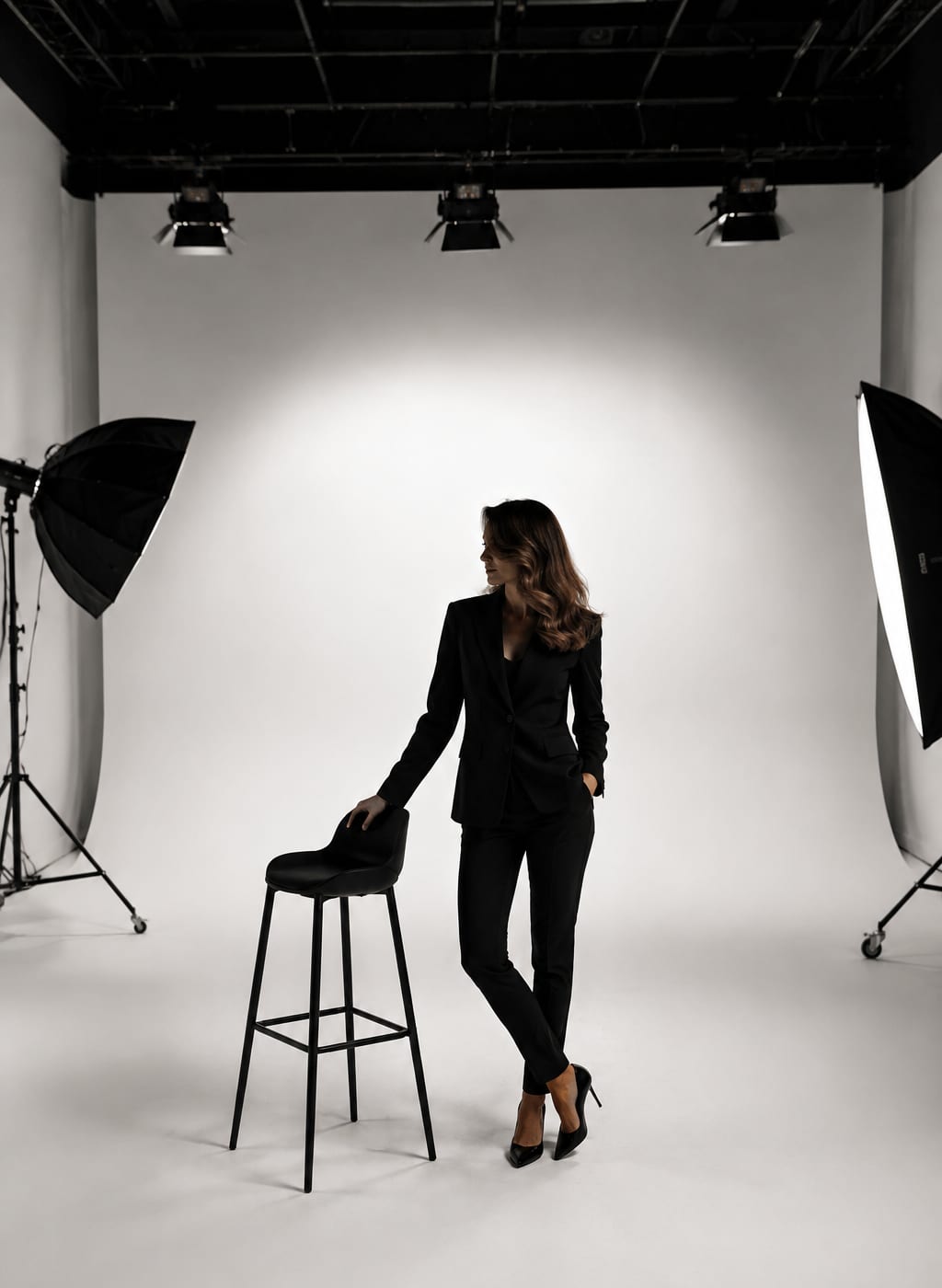 Paulina Haczykowska-Rosłonek w studiu fotograficznym, w czarnym garniturze, przy wysokim krześle